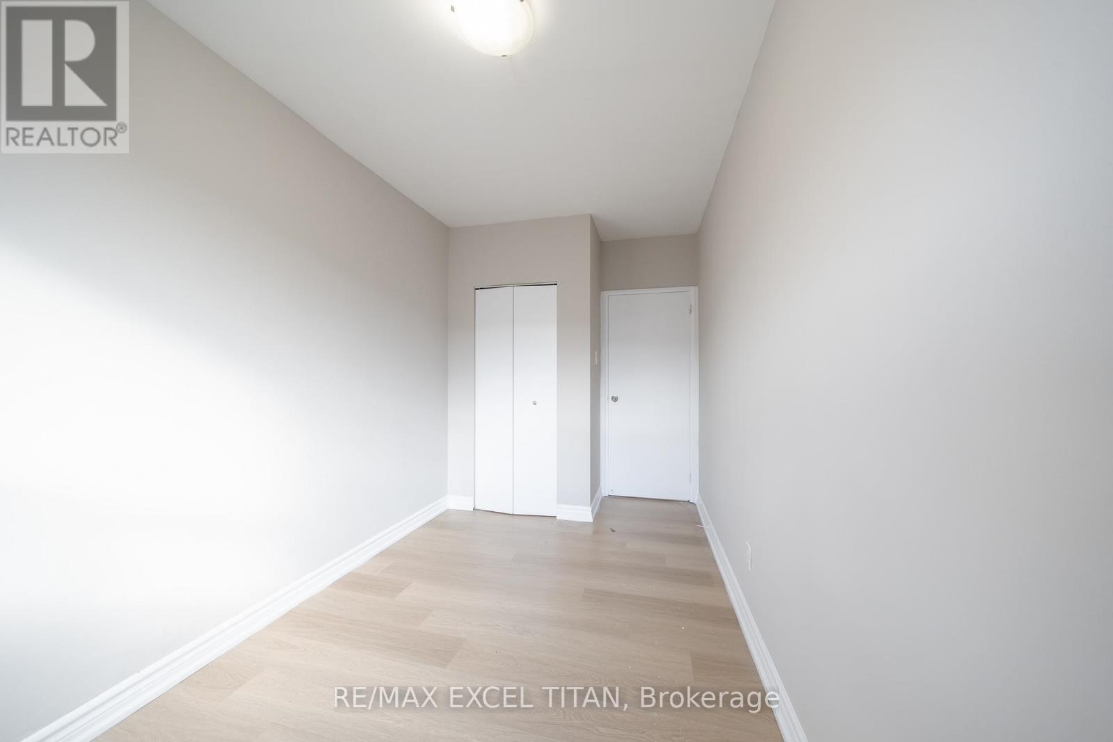 A white bedroom with a wooden floor and two white doors.