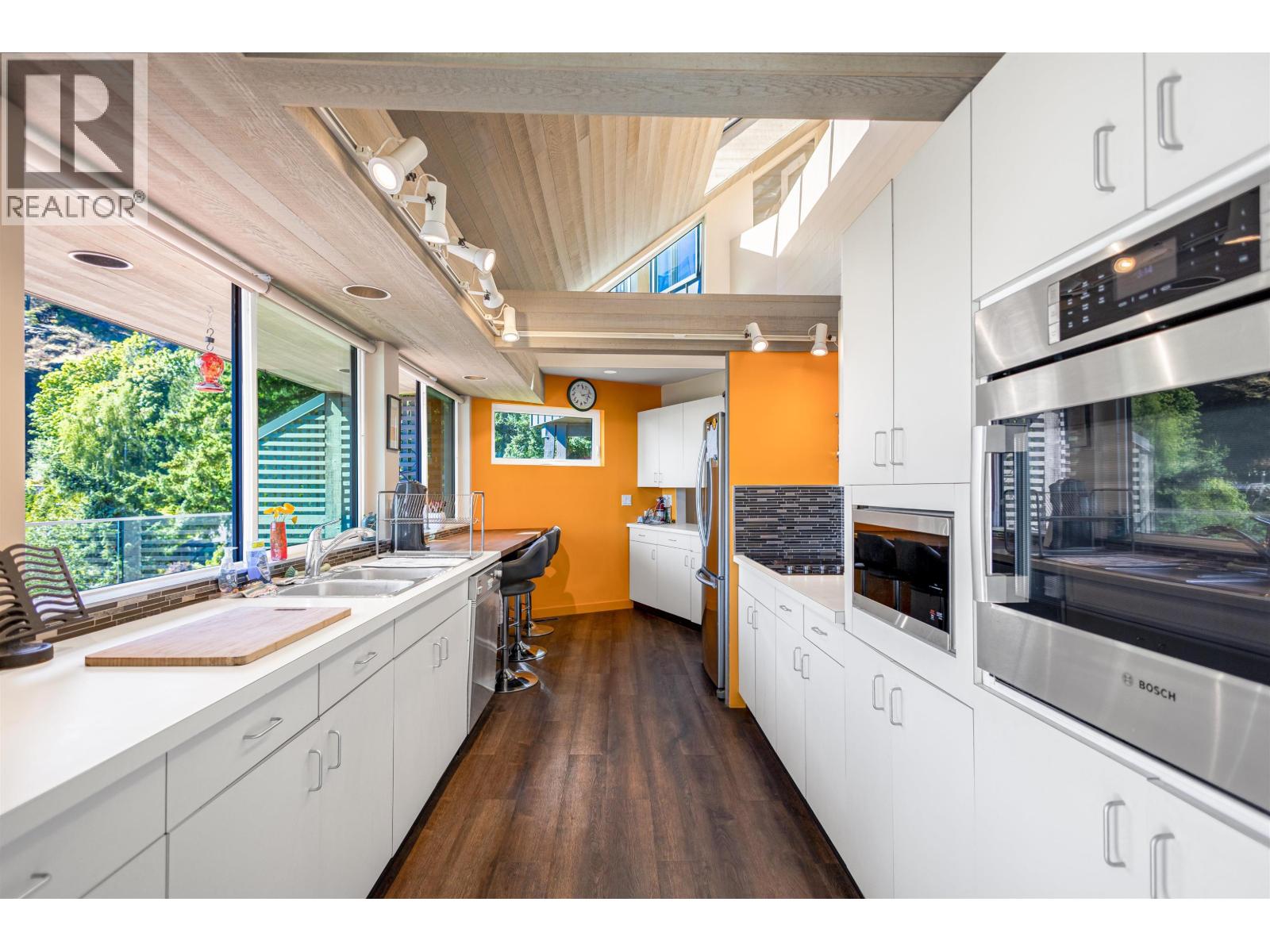 A modern kitchen with white cabinets and a wooden floor.