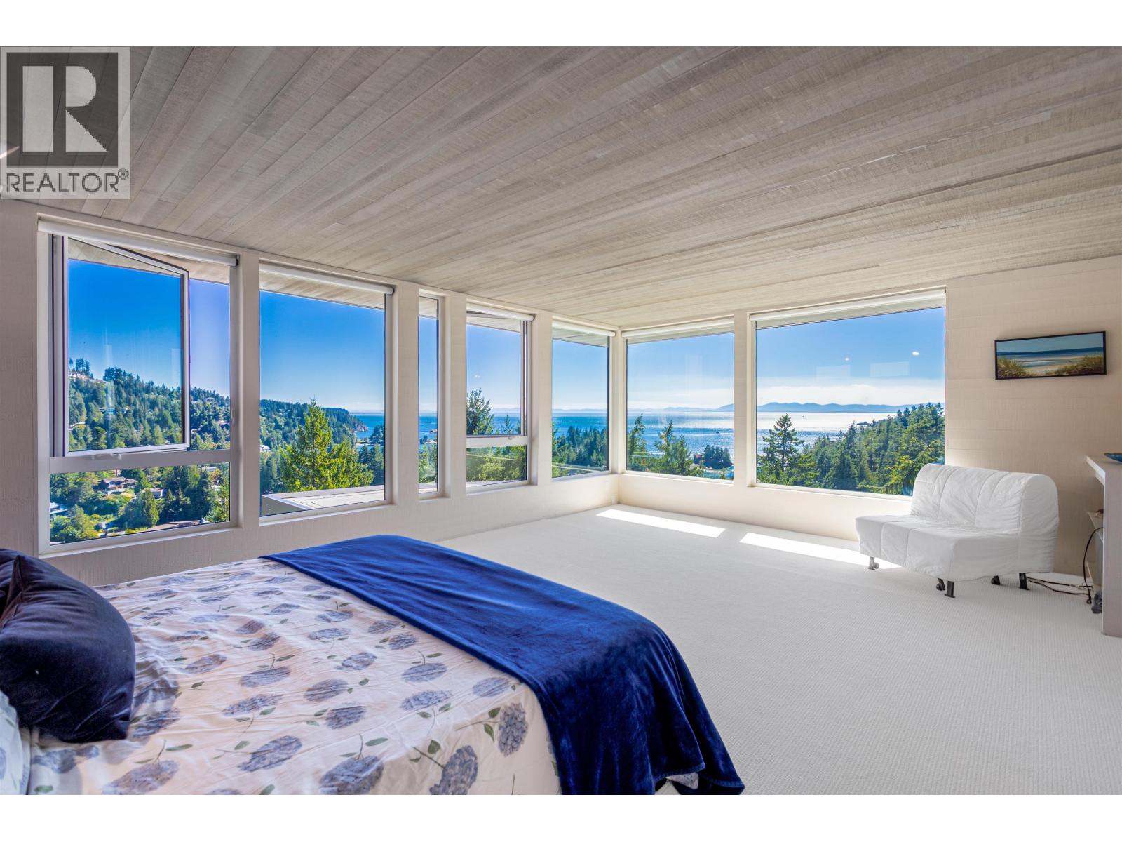 A bedroom with a large bed and a view of the forest.