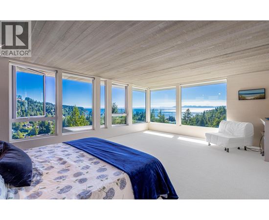 A bedroom with a large bed and a view of the forest.