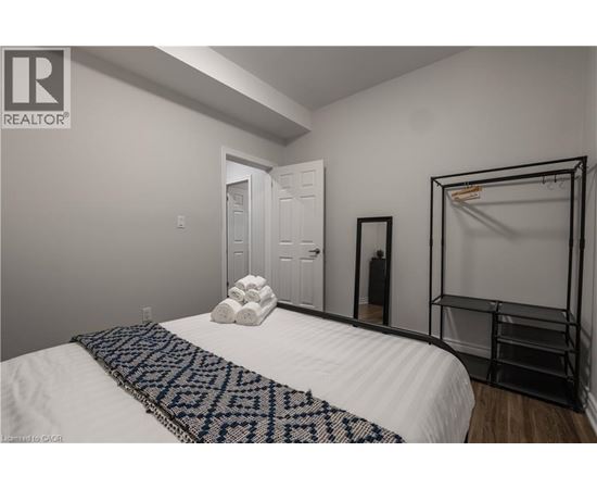 A bedroom with a white bed and a black and white patterned throw.