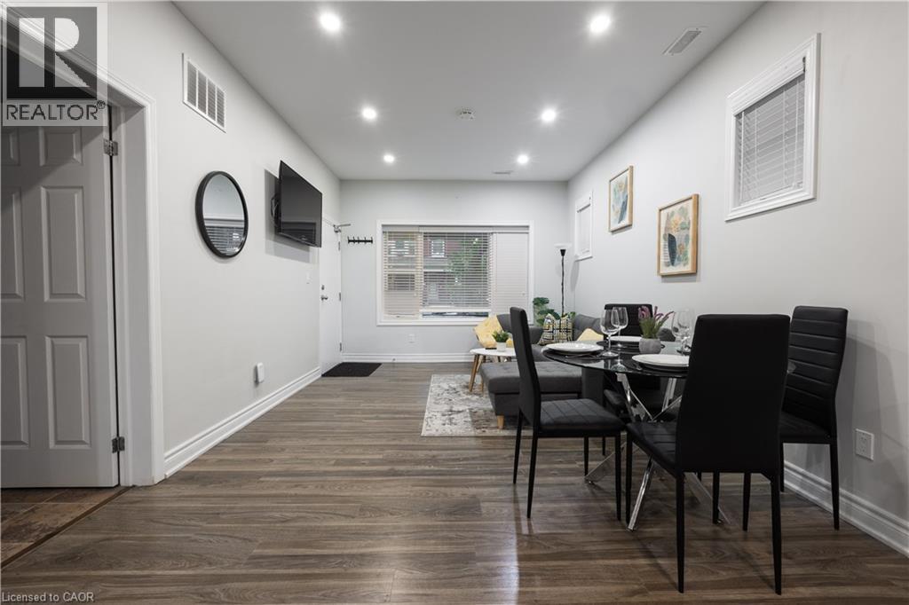 A dining room with a table set for two and a television mounted on the wall.