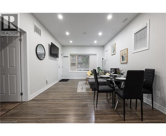 A dining room with a table set for two and a television mounted on the wall.