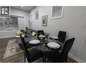 A dining room with a glass table and black chairs.