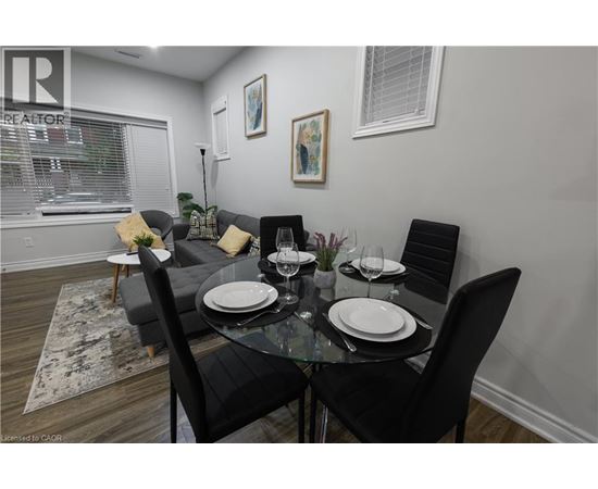 A dining room with a glass table and black chairs.