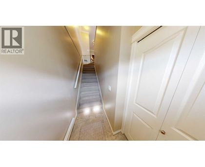 A hallway with a staircase leading to a door.