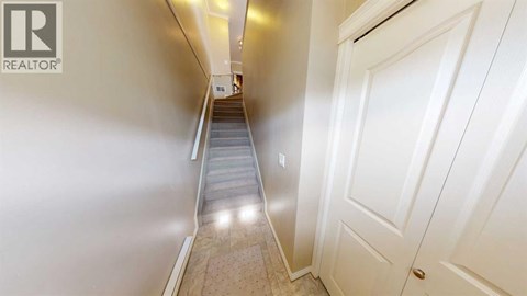 A hallway with a staircase leading to a door.