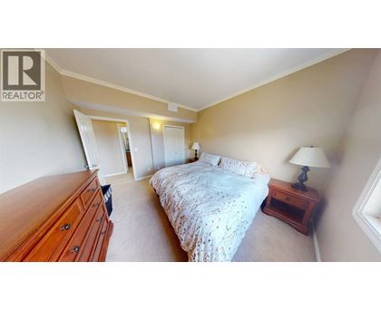 A bedroom with a bed, nightstand, and lamp.