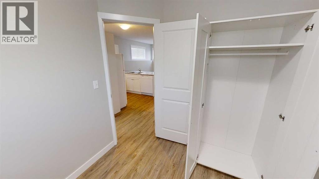 A white bedroom with a wardrobe and a small room visible through the open door.