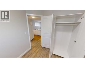 A white bedroom with a wardrobe and a small room visible through the open door.