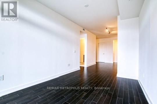 A spacious room with wooden flooring and white walls.