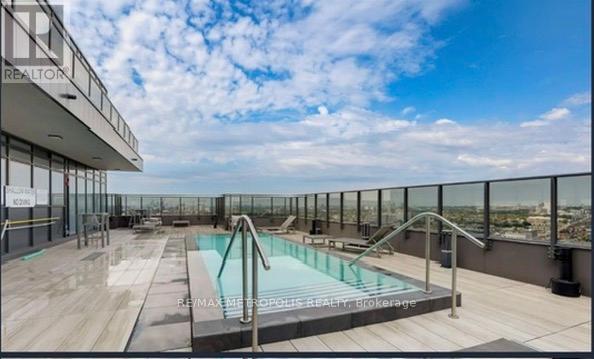 A rooftop pool area with a glass railing and a clear blue sky.
