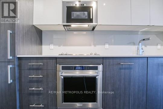 A modern kitchen with a stainless steel oven and microwave above it.