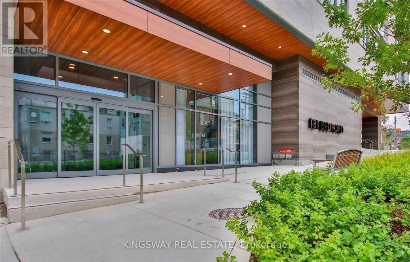 The front of a building with a glass entrance and a wooden roof.