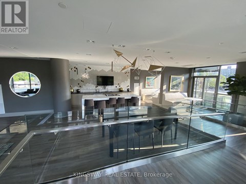 A modern living room with a glass table and a TV on the wall.