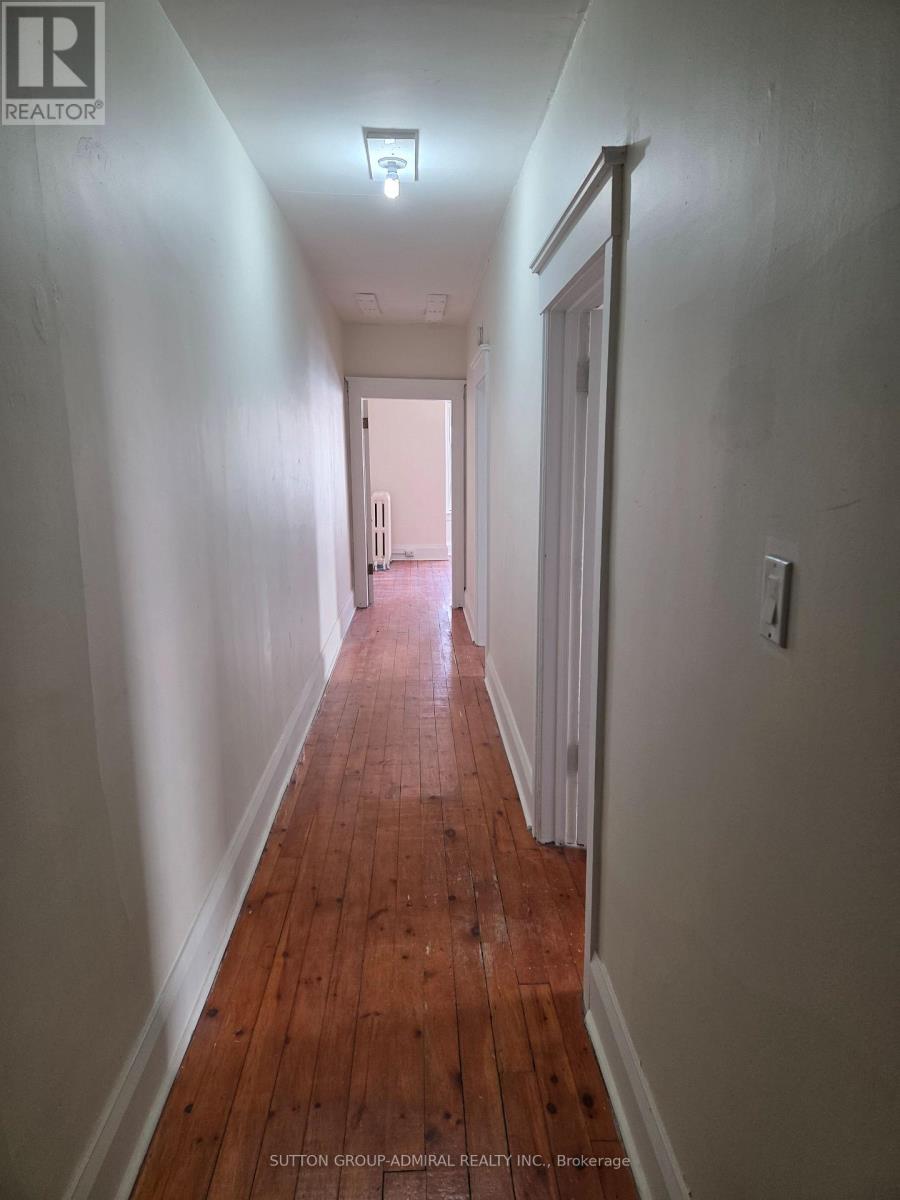 A long hallway with wood floors and white walls.