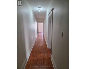 A long hallway with wood floors and white walls.
