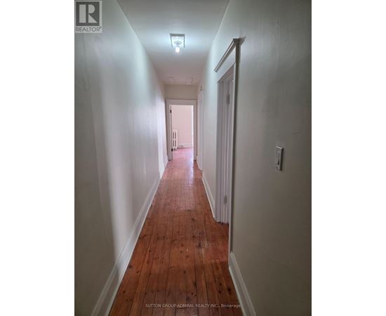 A long hallway with wood floors and white walls.