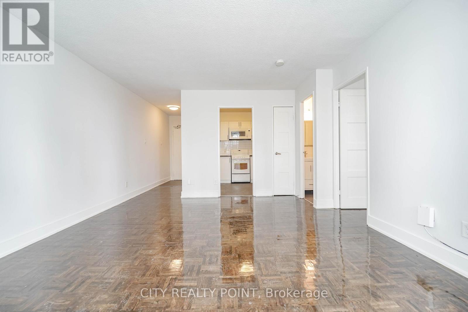 A spacious room with wooden flooring and white walls.