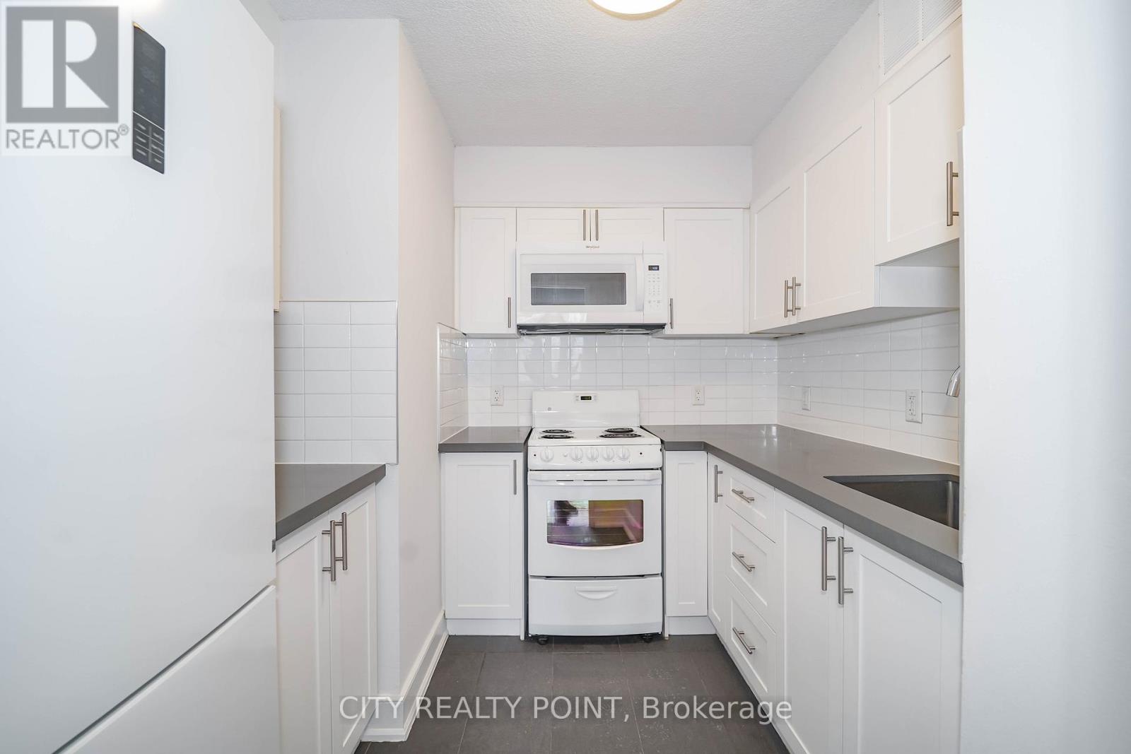 A white kitchen with a stove top oven and microwave.