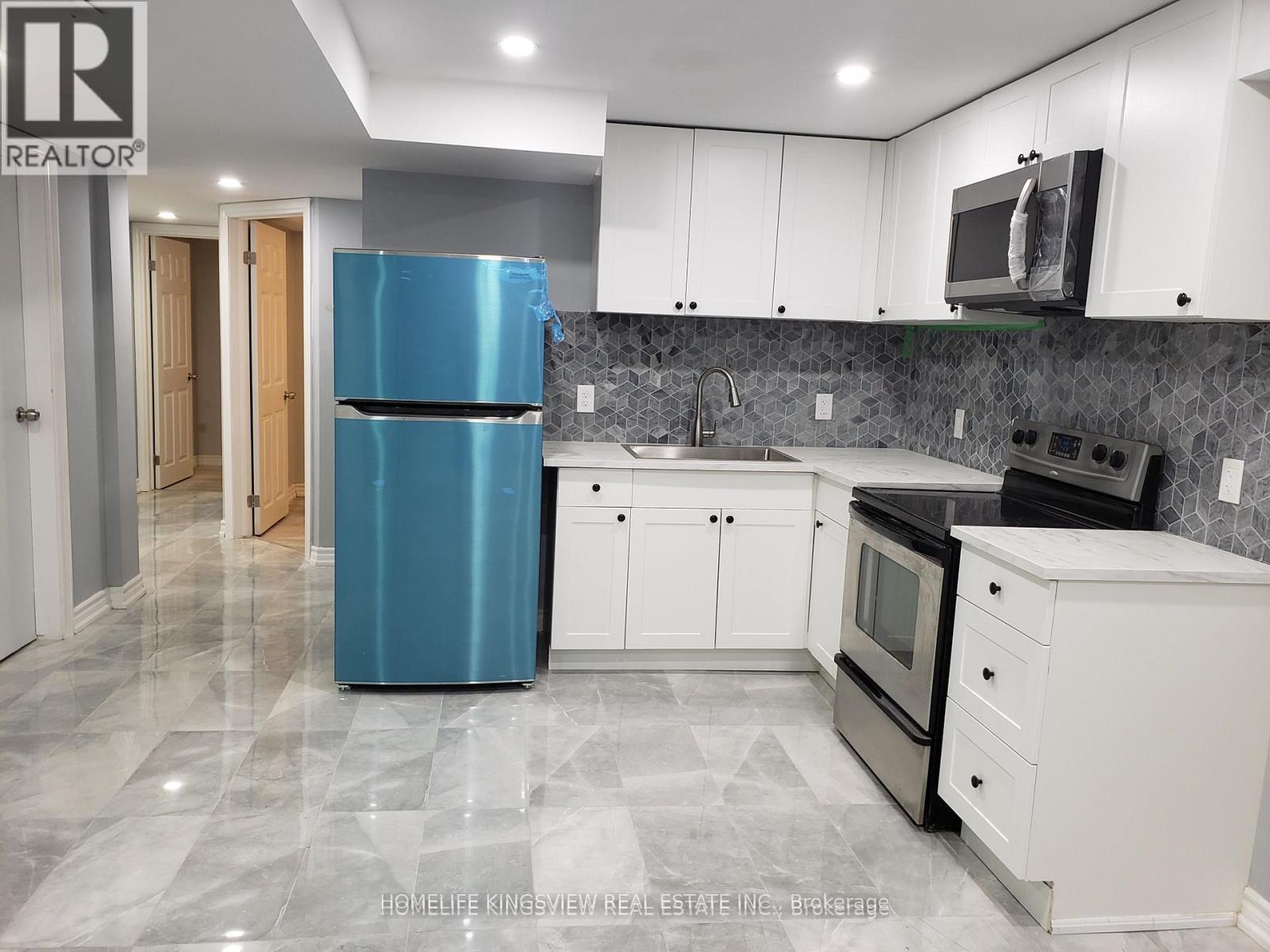 A kitchen with a blue refrigerator and white cabinets.