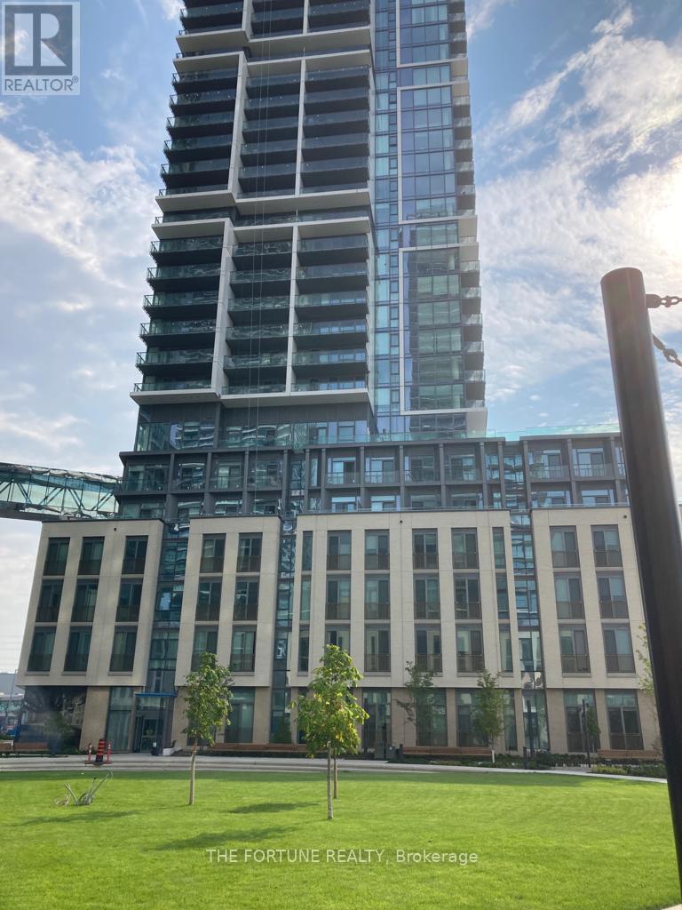 A tall building with a glass facade stands in front of a smaller building with a metal framework.