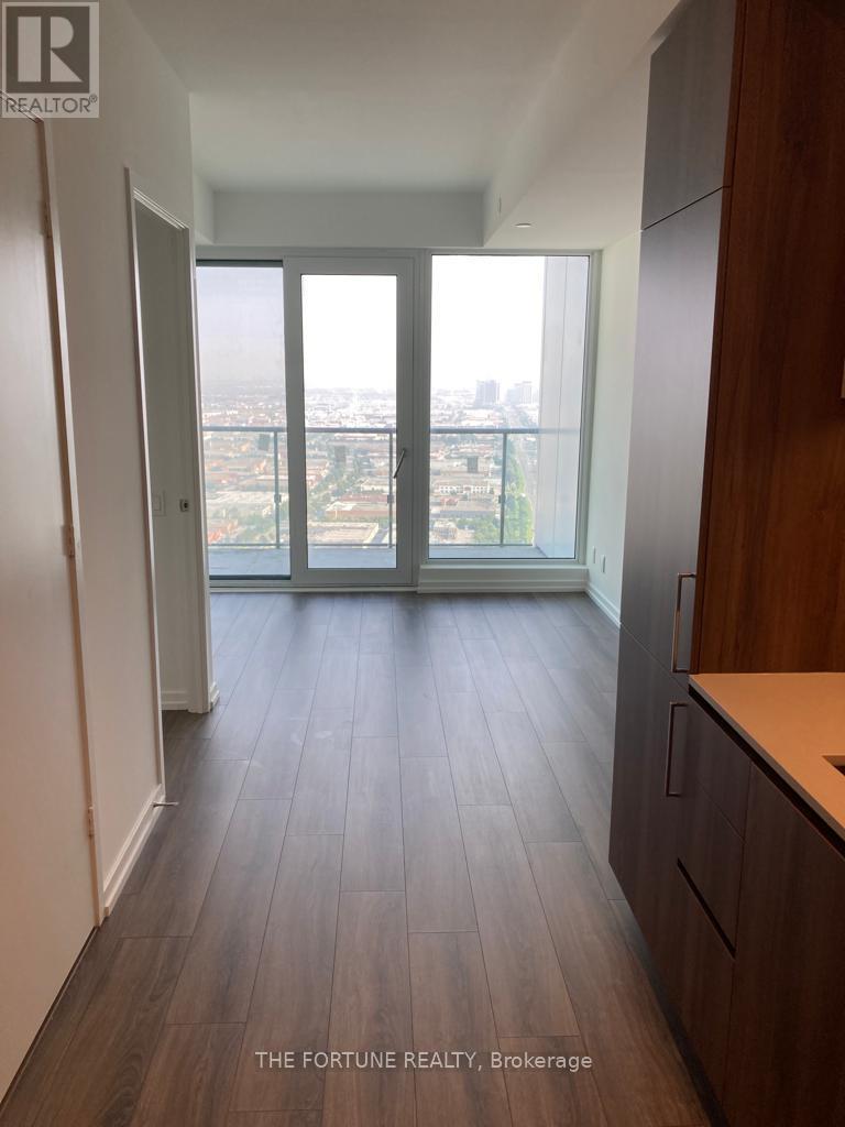 A hallway with wood flooring and a view of the city through a sliding glass door.