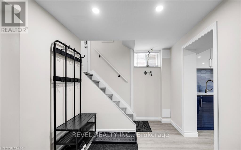 A white hallway with a staircase and a black railing.