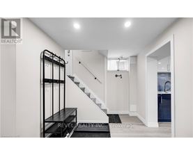 A white hallway with a staircase and a black railing.