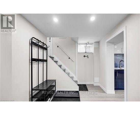 A white hallway with a staircase and a black railing.