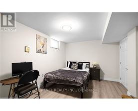 A bedroom with a bed, chair, and a painting on the wall.