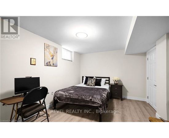 A bedroom with a bed, chair, and a painting on the wall.