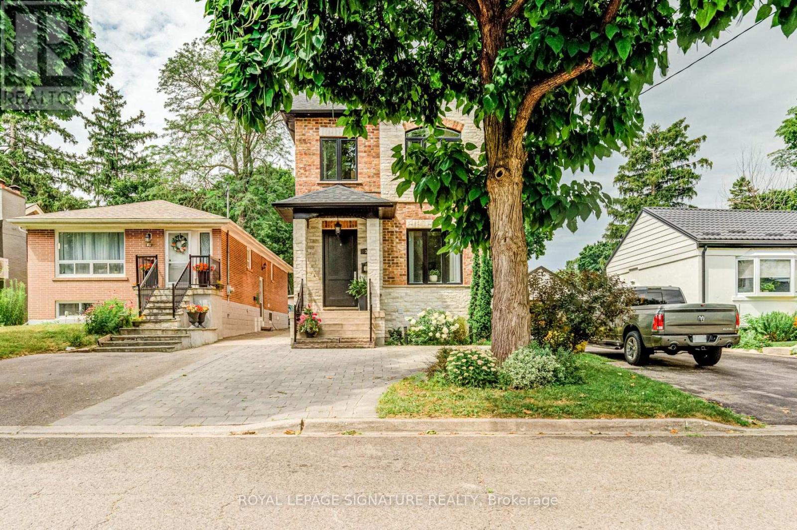 A house with a brick chimney and a tree in front.