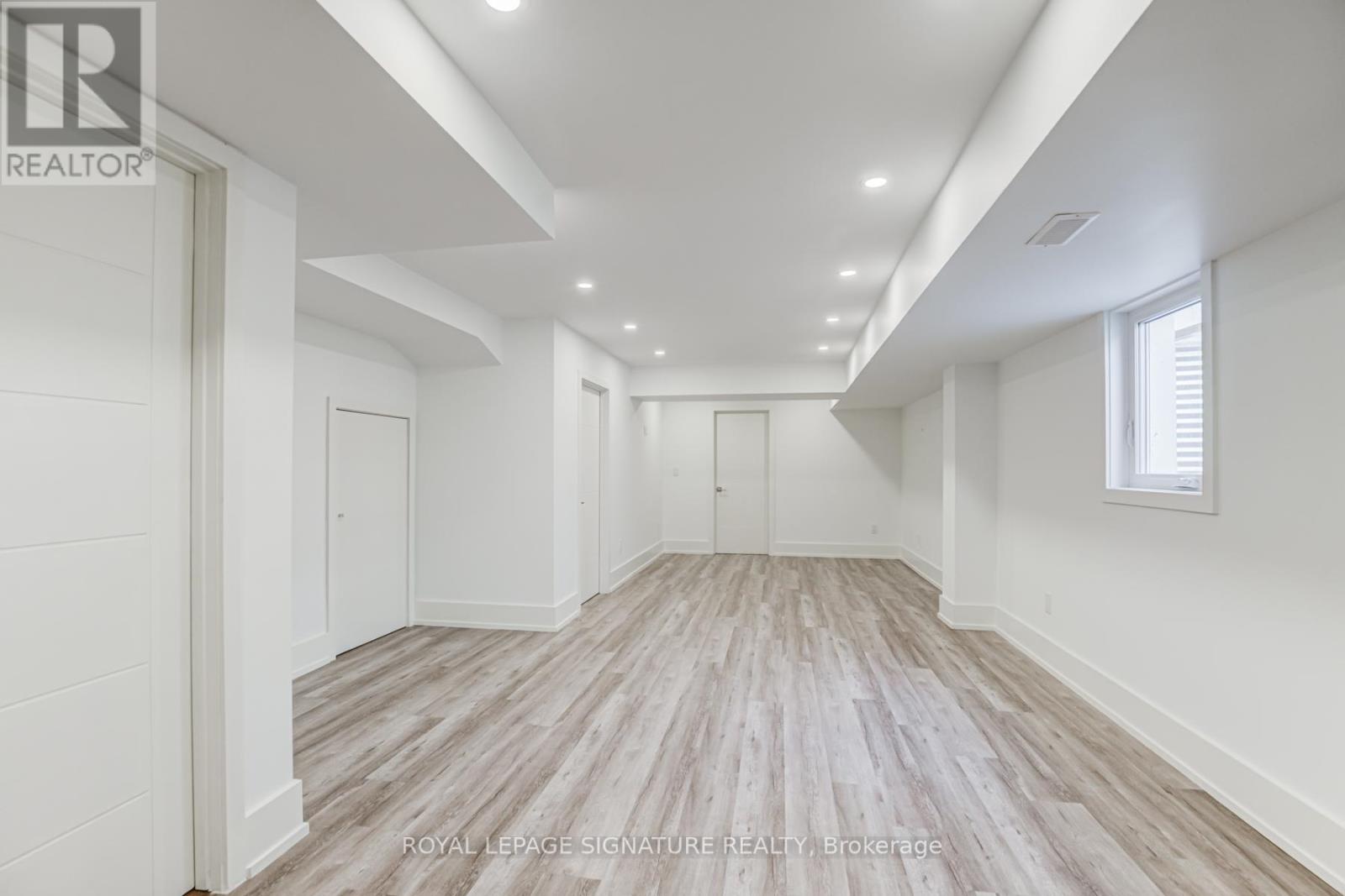 A spacious room with wooden flooring and white walls.