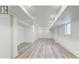 A spacious room with wooden flooring and white walls.