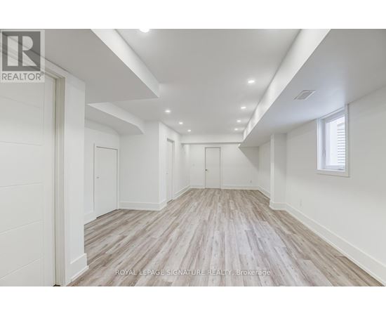 A spacious room with wooden flooring and white walls.