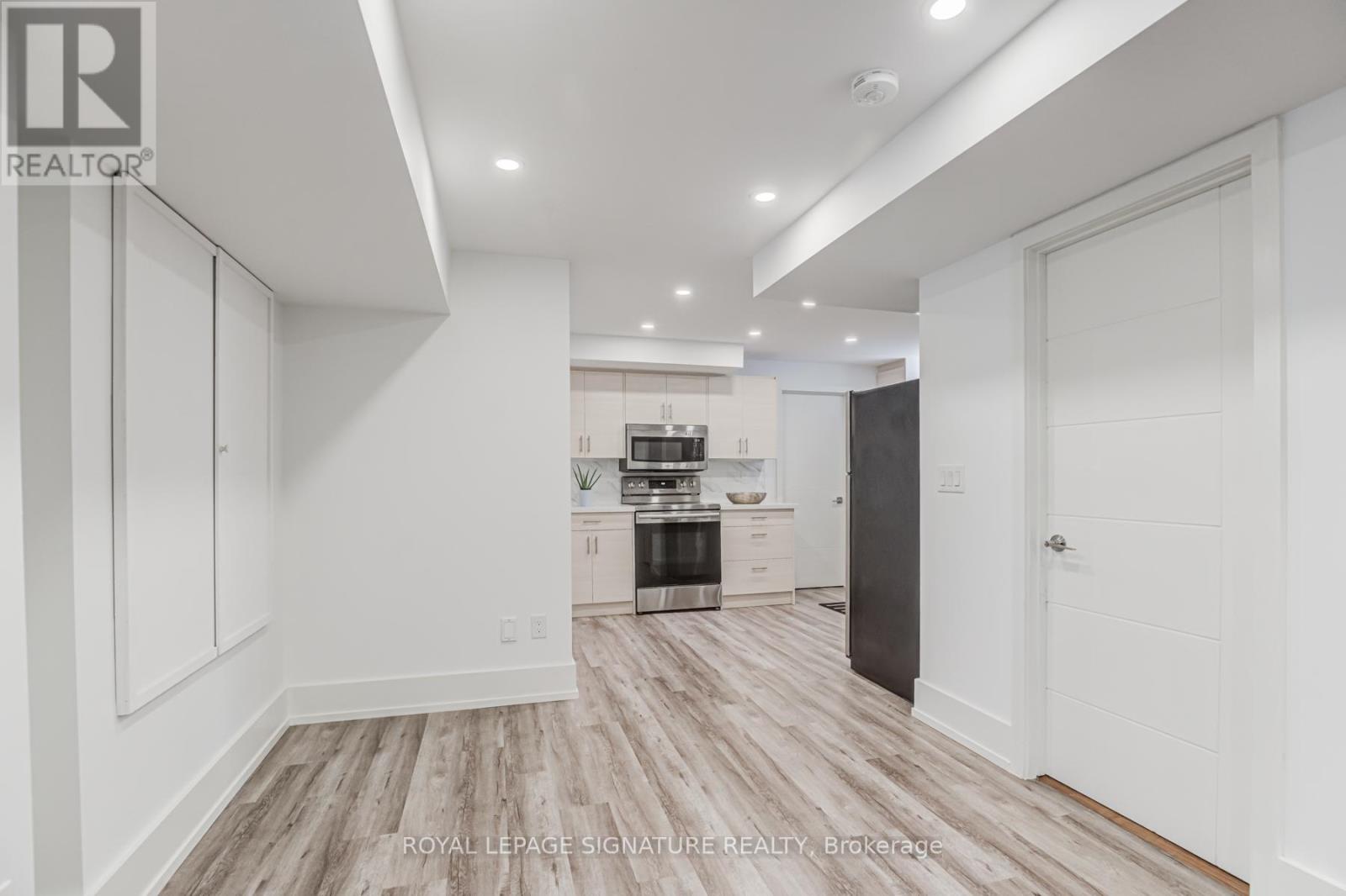 A spacious kitchen with white cabinets and a wooden floor.