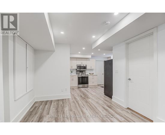 A spacious kitchen with white cabinets and a wooden floor.
