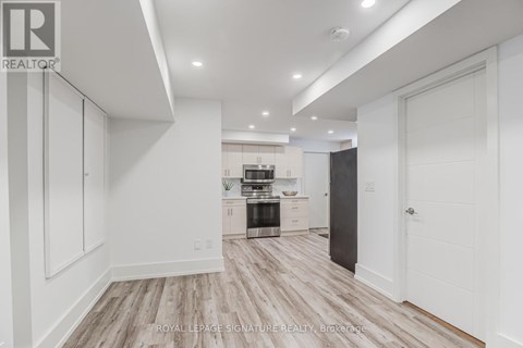A spacious kitchen with white cabinets and a wooden floor.