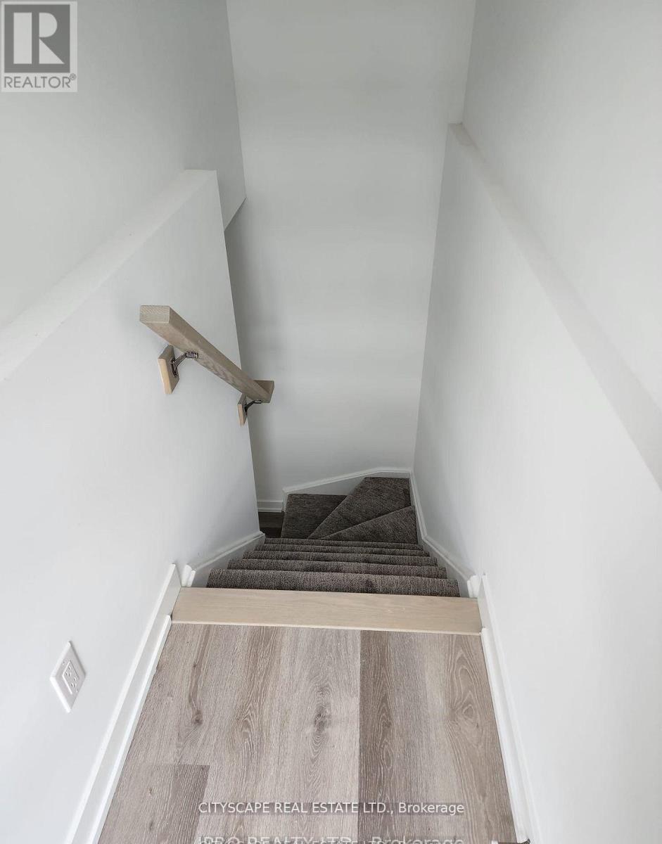 A staircase with a wooden handrail and a carpeted stair runner.