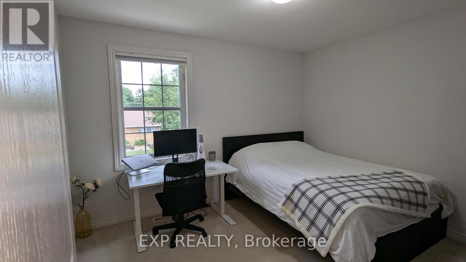 A bedroom with a bed, desk, and chair.
