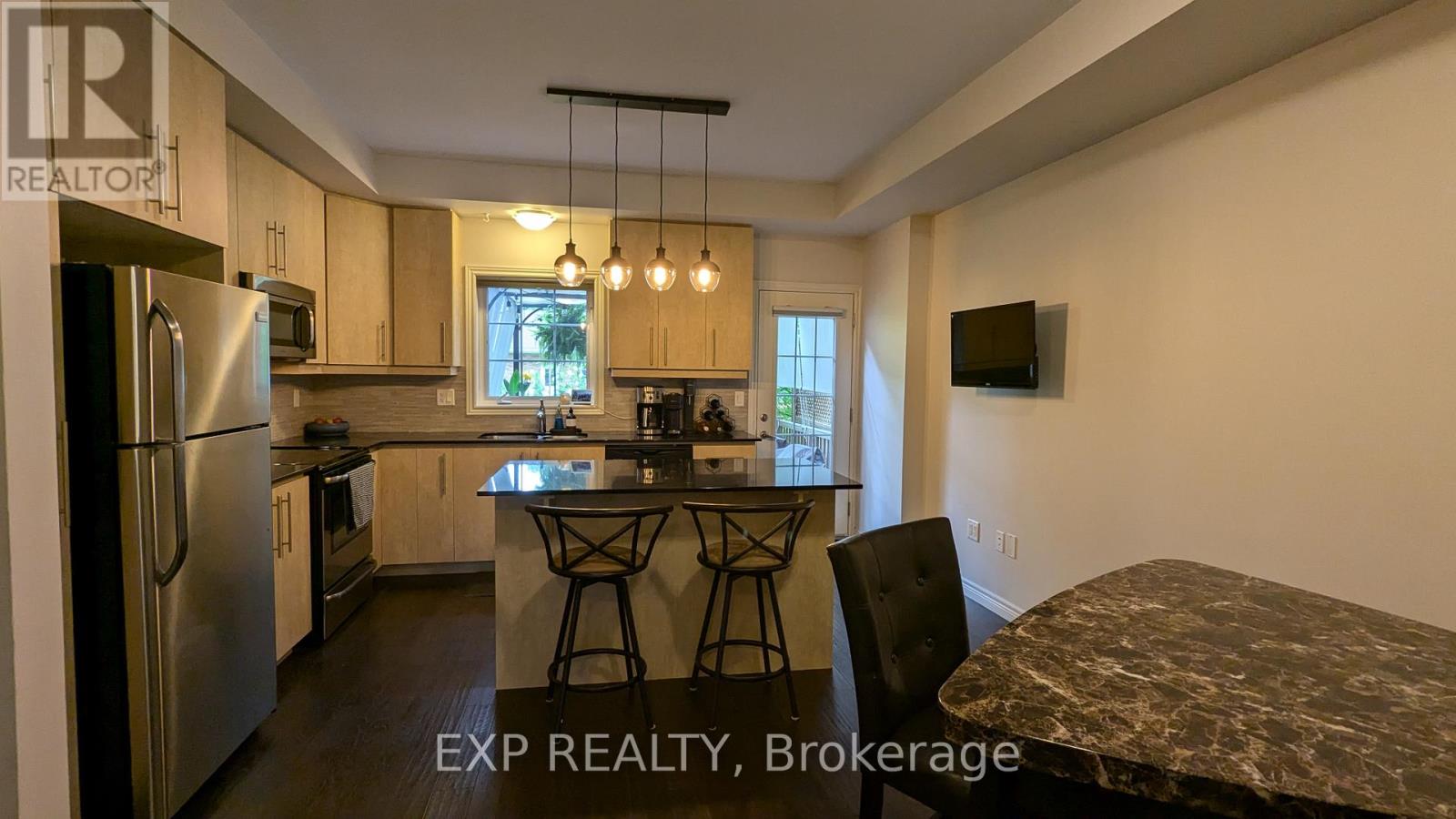 A kitchen with a refrigerator, microwave, and a dining table with chairs.