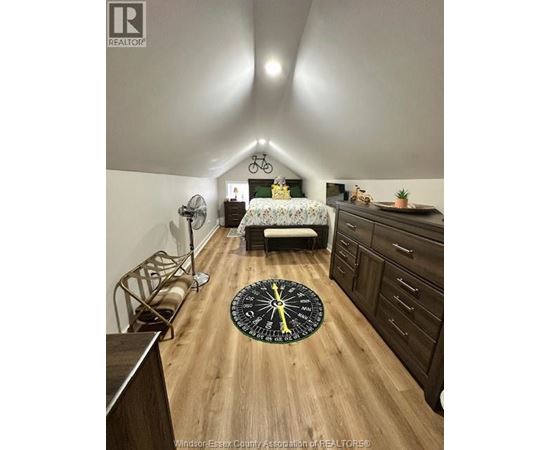 A bedroom with a bed, dresser, and a bicycle on the wall.