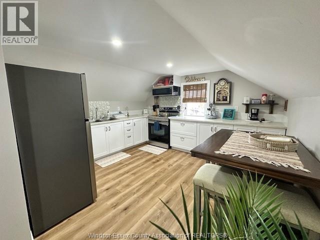 A kitchen with wooden floors and white cabinets.