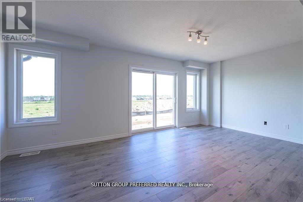 A spacious room with wooden flooring and large windows.