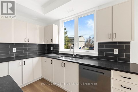 A kitchen with white cabinets and black countertops.