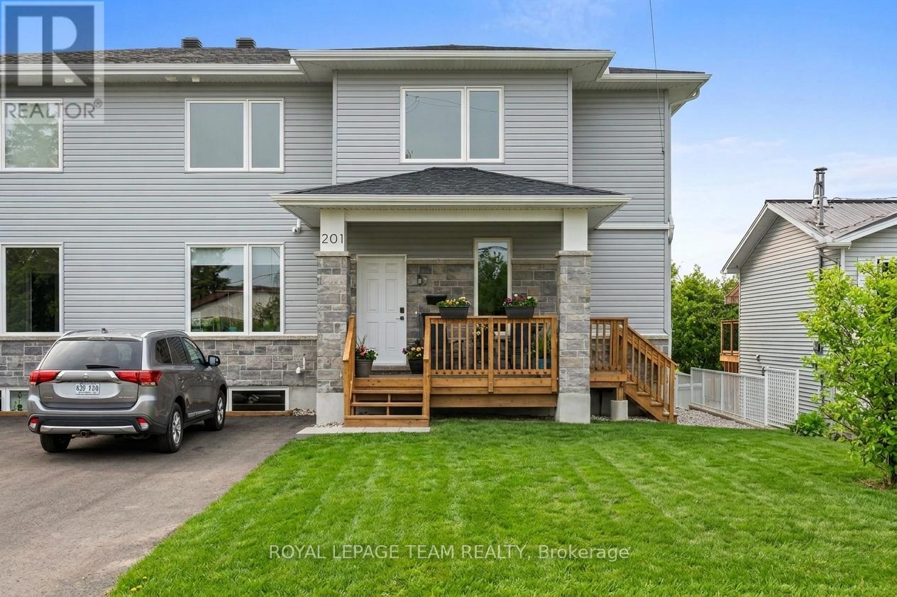 A grey house with a wooden deck and a car parked in front.