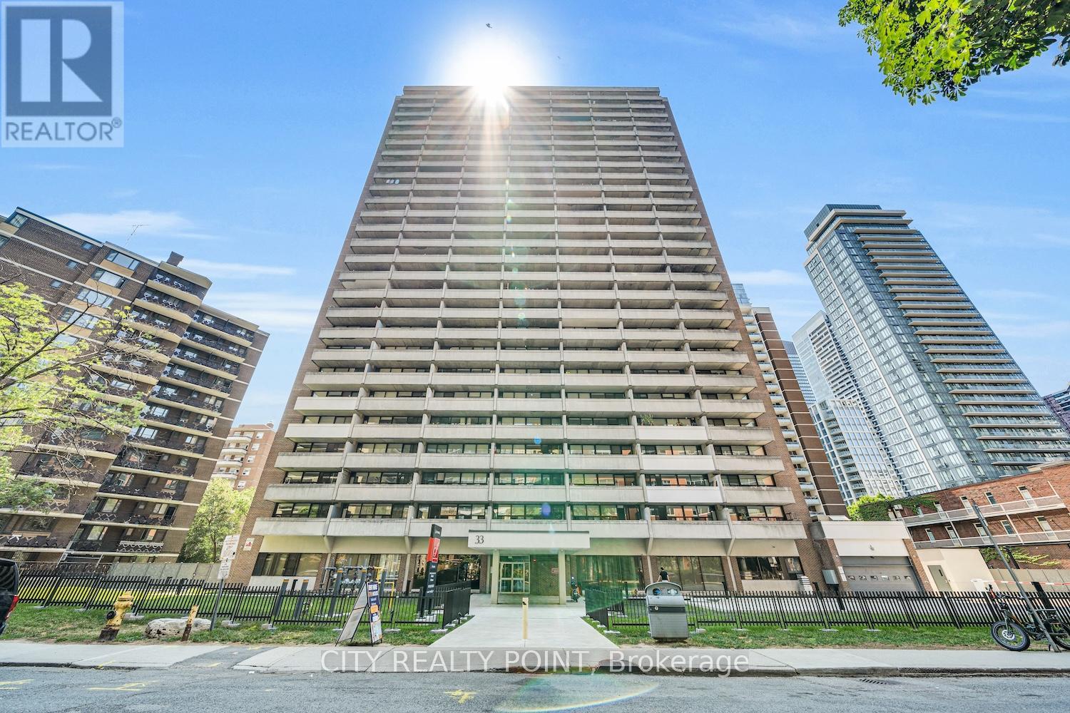 A tall building with a sun shining in the background.