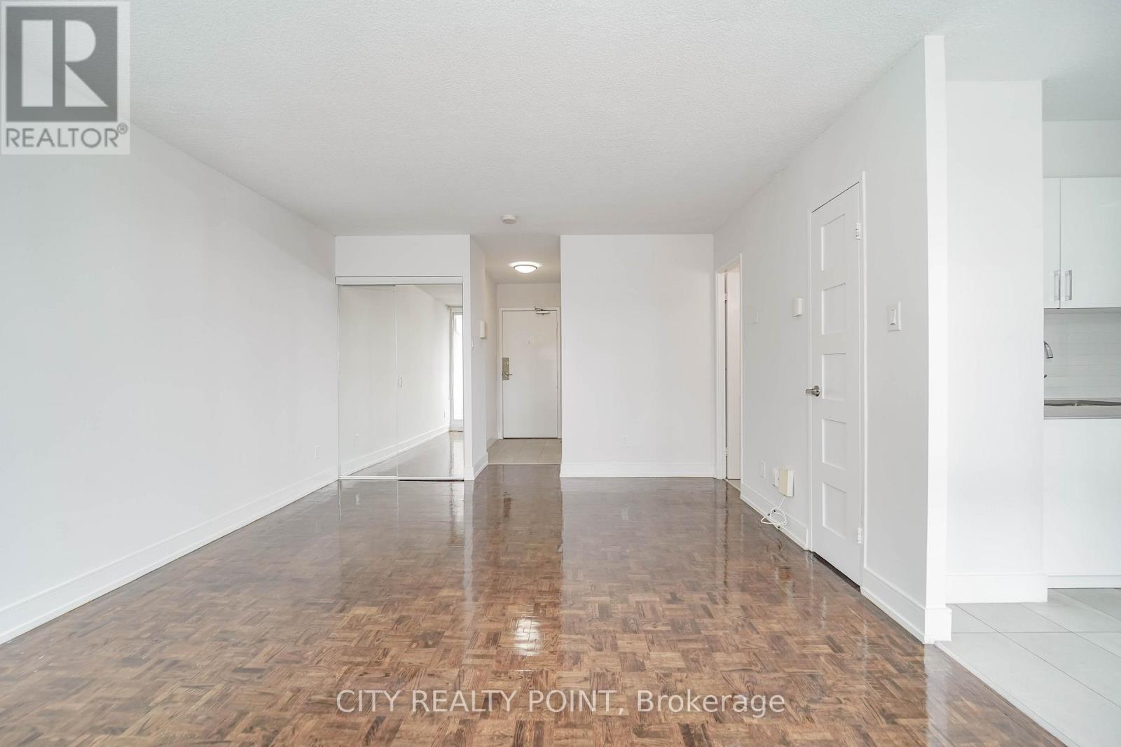 A spacious room with wooden flooring and white walls.