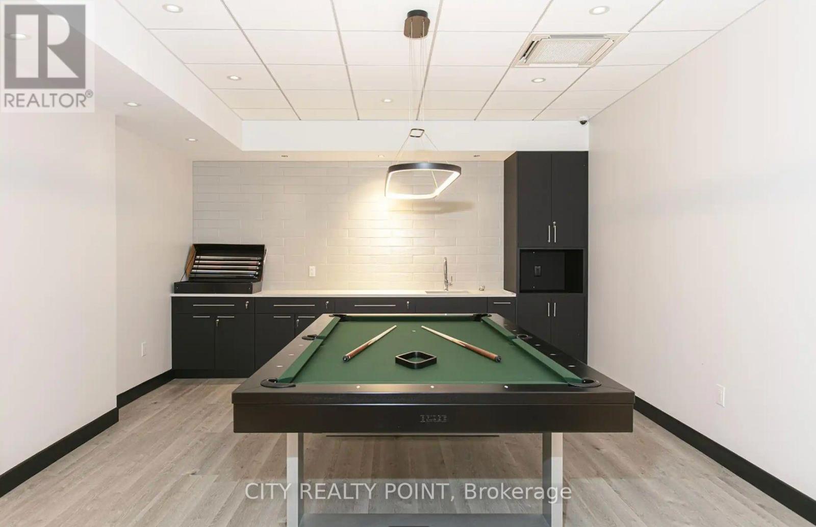 A pool table in a room with a realtor sign.